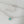 A collection of dainty mini opal charm necklaces laid out on a soft surface, showcasing variations in gold plating colors.