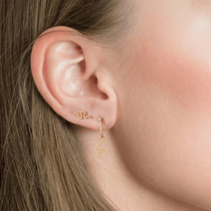 Woman wearing earrings designed to resemble a snake, with a gold plating on sterling silver