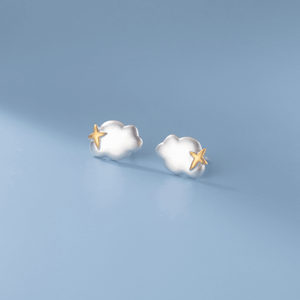 Pair of cloud-shaped earrings with gold stars on a light blue background