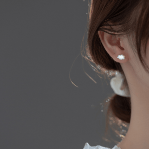 Close-up of a person wearing a delicate earring with a dark background