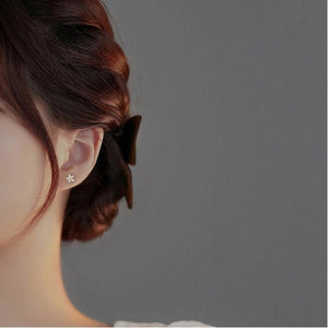 Close-up of an ear with a bow in hair against a gray background