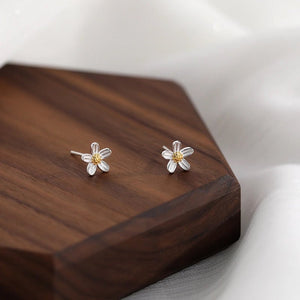 Flower-shaped earrings on a wooden surface
