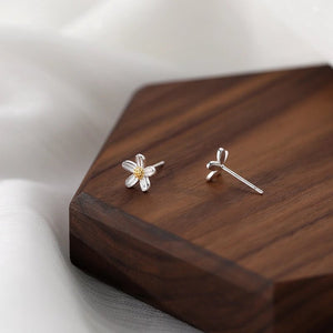 Silver flower-shaped earrings on a wooden surface