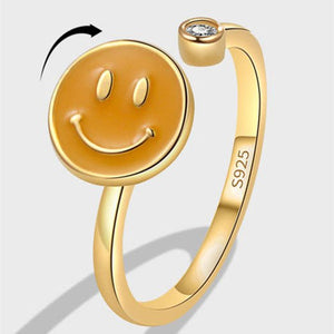 Gold ring with a smiley face design on a light gray background