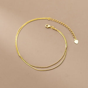 Gold necklace with a heart-shaped pendant on a beige background