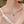Necklace with a pendant worn by a person in a white top against a blurred background
