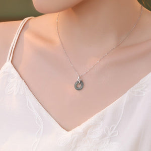 Silver necklace with a pendant on a model wearing a white top.