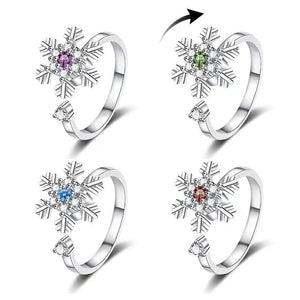 Four snowflake-shaped rings with colored gemstones on a white background