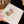 Gold ring with diamond-like stones on a white card held by a hand.