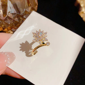 Gold ring with diamond-like stones on a white card held by a hand.