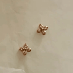 Gold earrings with pink gemstones on a beige background