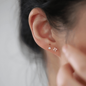 Close-up of an ear wearing two small earrings with a blurred background