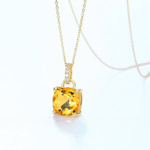 Gold necklace with a yellow gemstone pendant on a white background
