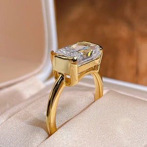 Gold ring with a large diamond on a beige surface