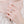 Close-up of a hand wearing a delicate silver ring with a small gemstone on a soft pink background.