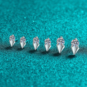 Six silver earrings with clear gemstones on a teal glittery background
