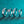 Four silver rings with diamond-like stones on a teal glittery background