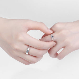 Two hands wearing silver rings with diamond accents on a light gray background