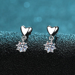 Heart-shaped earrings with clear gemstones on a dark blue background