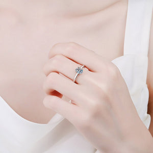 Close-up of a hand wearing a silver ring with a heart-shaped gemstone on a light background