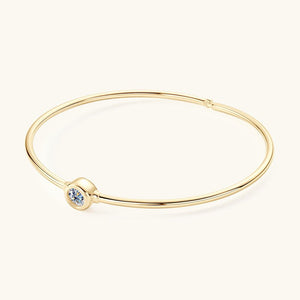 Gold bracelet with a small round gemstone on a white background