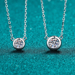 Two silver necklaces with round diamond pendants on a teal background