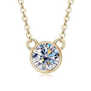 A round moissanite charm necklace with a gold-colored frame on a silver chain, showcasing a single large clear gemstone.