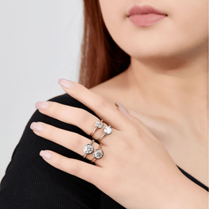 Close-up of a hand wearing multiple diamond rings on a plain background