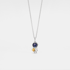 A silver and gold necklace featuring a spaceman and moon charm with a gold plating on a sterling silver base.
