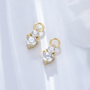 Gold earrings with clear gemstones on a light gray background