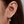 Close-up of an ear wearing a gold earring with a small diamond.