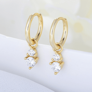 Gold hoop earrings with clear gemstones on a soft white background