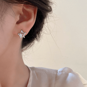 Star-shaped earrings worn by a person with a neutral background