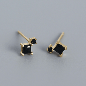 Gold earrings with black gemstones on a gray background