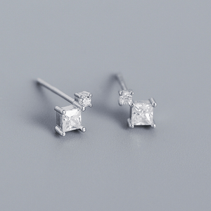 Pair of silver square-cut stud earrings on a gray background