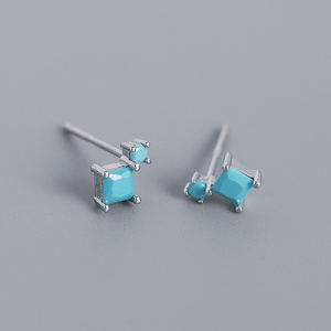 Pair of turquoise square stud earrings on a gray background