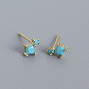 Gold earrings with turquoise stones on a gray background