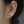 Close-up of an ear wearing a green gemstone earring with a blurred background