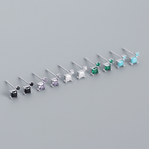 Set of small stud earrings with colored gemstones on a gray background
