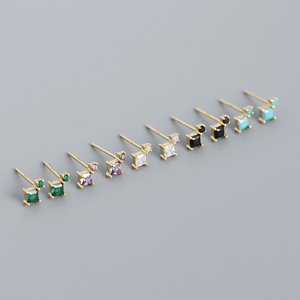 Set of gold stud earrings with various gemstones on a gray background