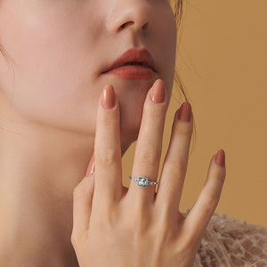 Close-up of a woman's hand wearing an engagement ring with a yellow background