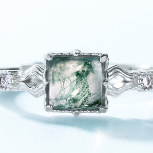 Silver ring with a green gemstone on a light blue background