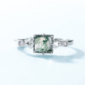 Silver ring with a green gemstone on a white background