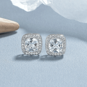Pair of silver stud earrings with clear gemstones on a light blue background