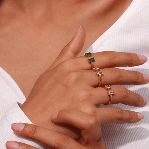 Close-up of a hand wearing multiple rings with gemstones on a white background