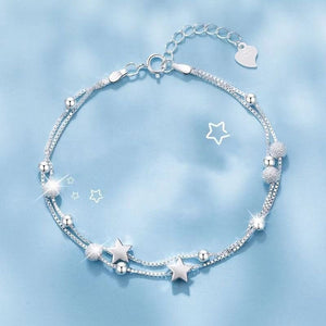 Silver bracelet with star and heart charms on a light blue background