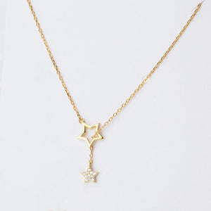 Gold star-shaped necklace on a light gray background