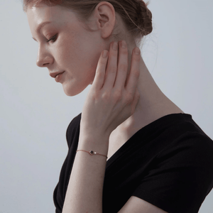 A model wearing a gold-plated bracelet made of sterling silver, featuring a central charm with a photo projection, complemented by smaller clear cubic zirconia on the chain.