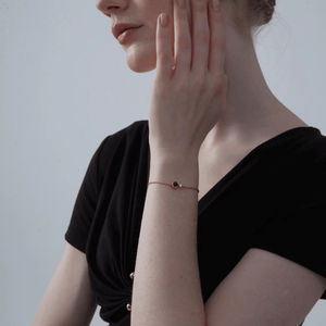 A model wearing a gold-plated bracelet made of sterling silver, featuring a central charm with a photo projection, complemented by smaller clear cubic zirconia on the chain.