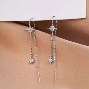 Silver star-shaped earrings on a beige surface